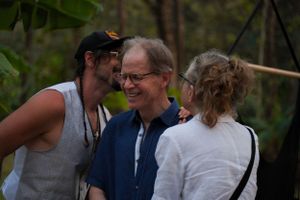 Three people sharing an intimate conversation and laughing together outdoors.