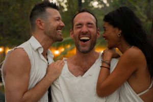 Three friends share a joyful moment of laughter outdoors at sunset.
