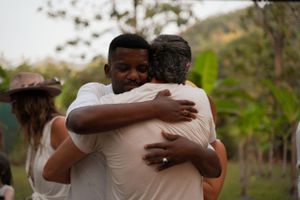 Two people embrace warmly in an emotional moment outdoors.