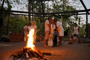 Group gathered around a bonfire during an outdoor evening celebration.