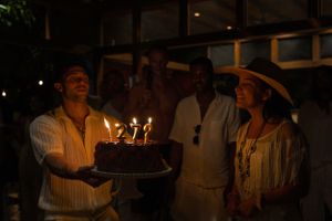 Birthday celebration with lit cake in a dimly lit outdoor setting.