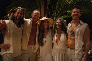 Friends in white clothing pose together at a tropical evening gathering.
