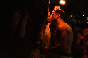 Couple sharing intimate moment during nighttime fire performance.