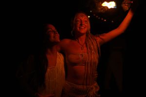 People celebrating with fire performers during nighttime outdoor event.
