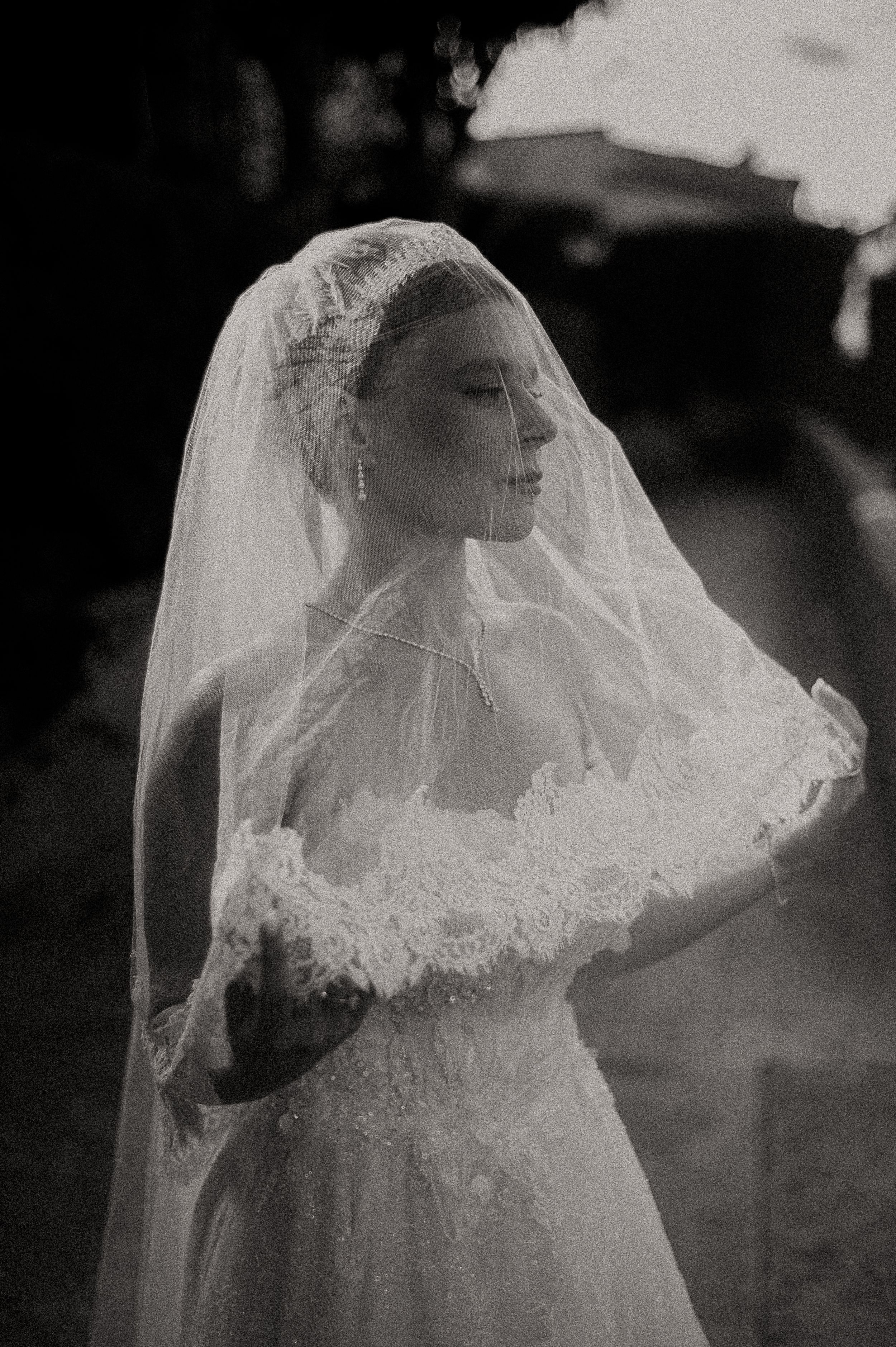 Ethereal black and white bridal portrait with flowing lace veil.
