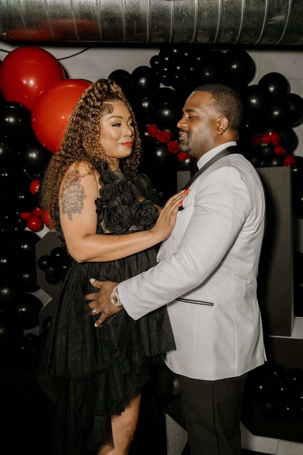 Couple dancing intimately at an event decorated with red and black balloons.