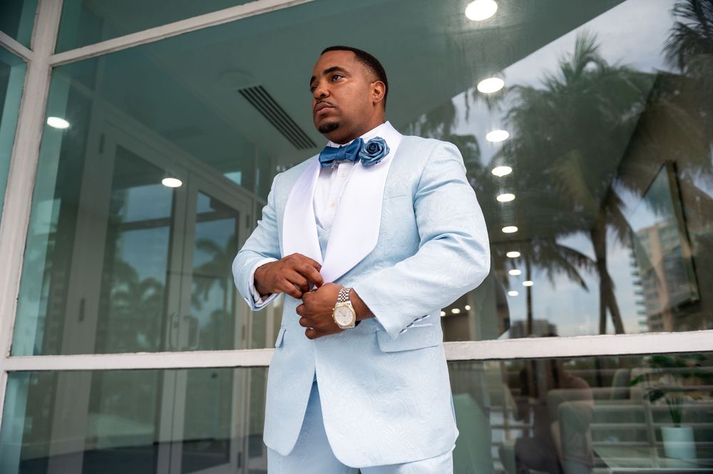 Close-up of groom adjusting tie in baby-blue suit for yacht wedding