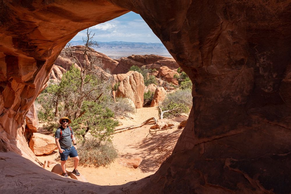 Red rock canyon formations frame a desert hiking trail under blue skies.