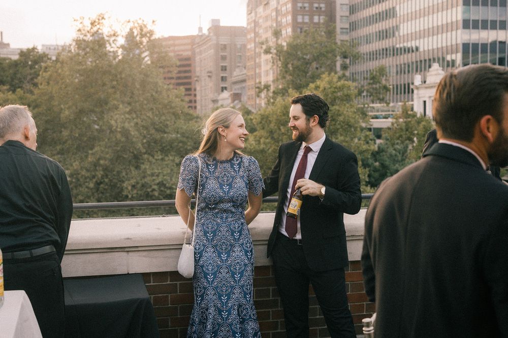 People gathering on an urban rooftop during sunset with city buildings in the background.
