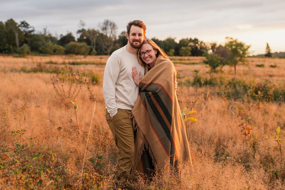 A couple sharing intimate moments in a golden field during sunset.