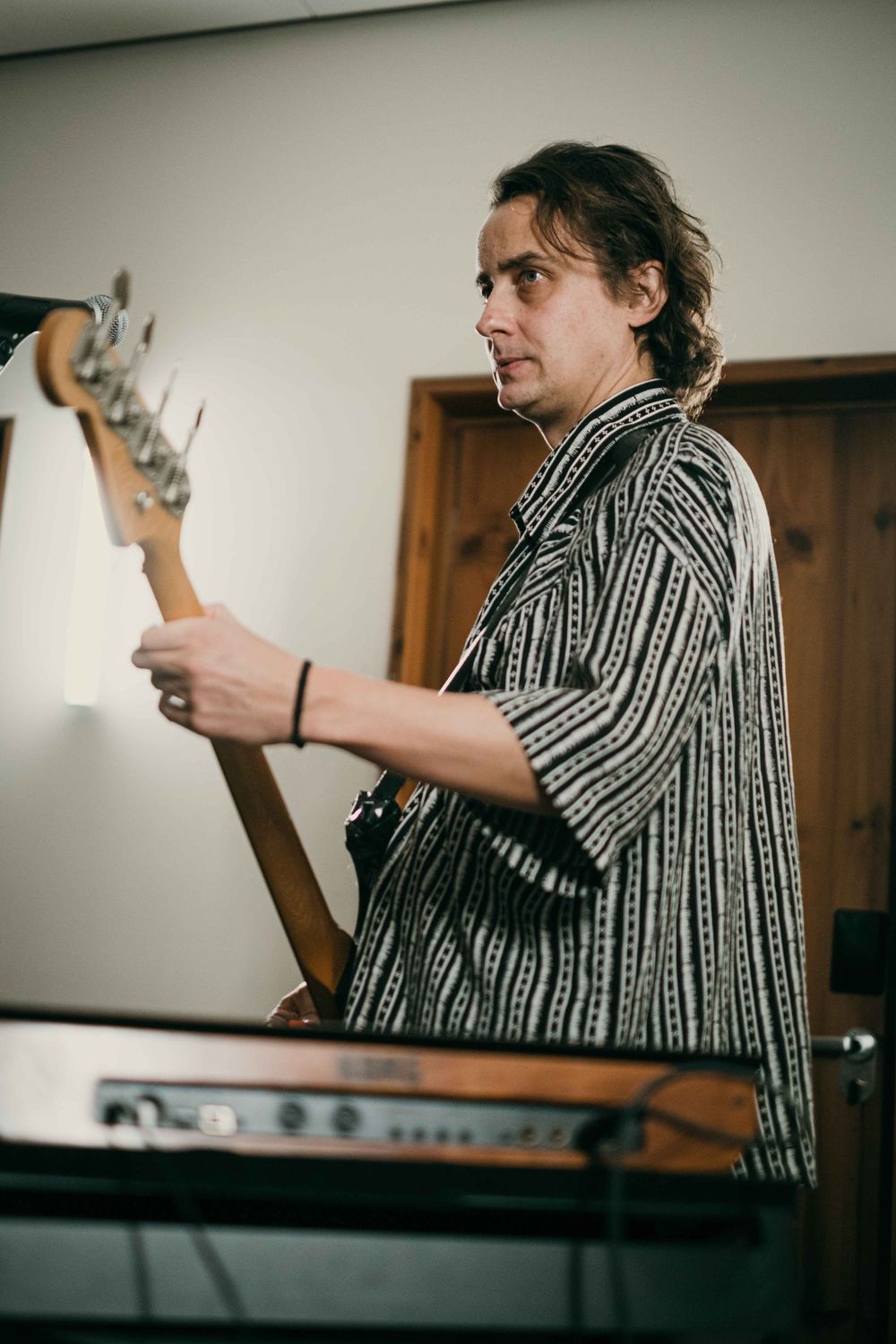 Artist playing keyboard and electronic instruments in studio setting.