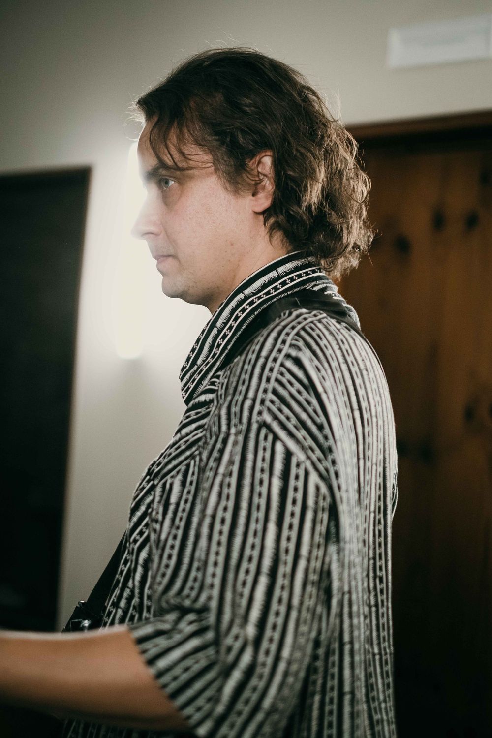 Side profile view of musician in striped pattern shirt during performance.