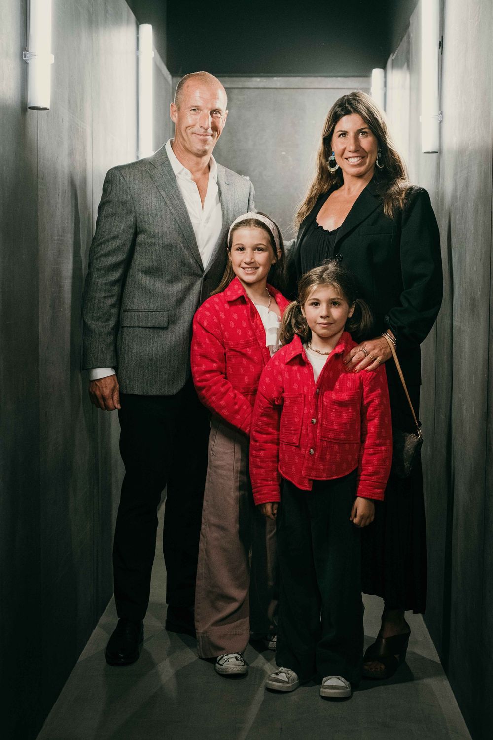 Group photo in a hallway with person wearing bright red jacket.