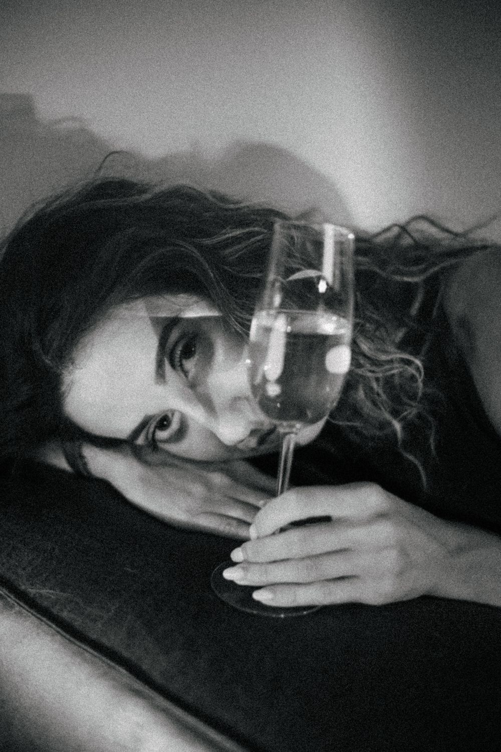 Artistic black and white portrait with glass and dramatic shadows.