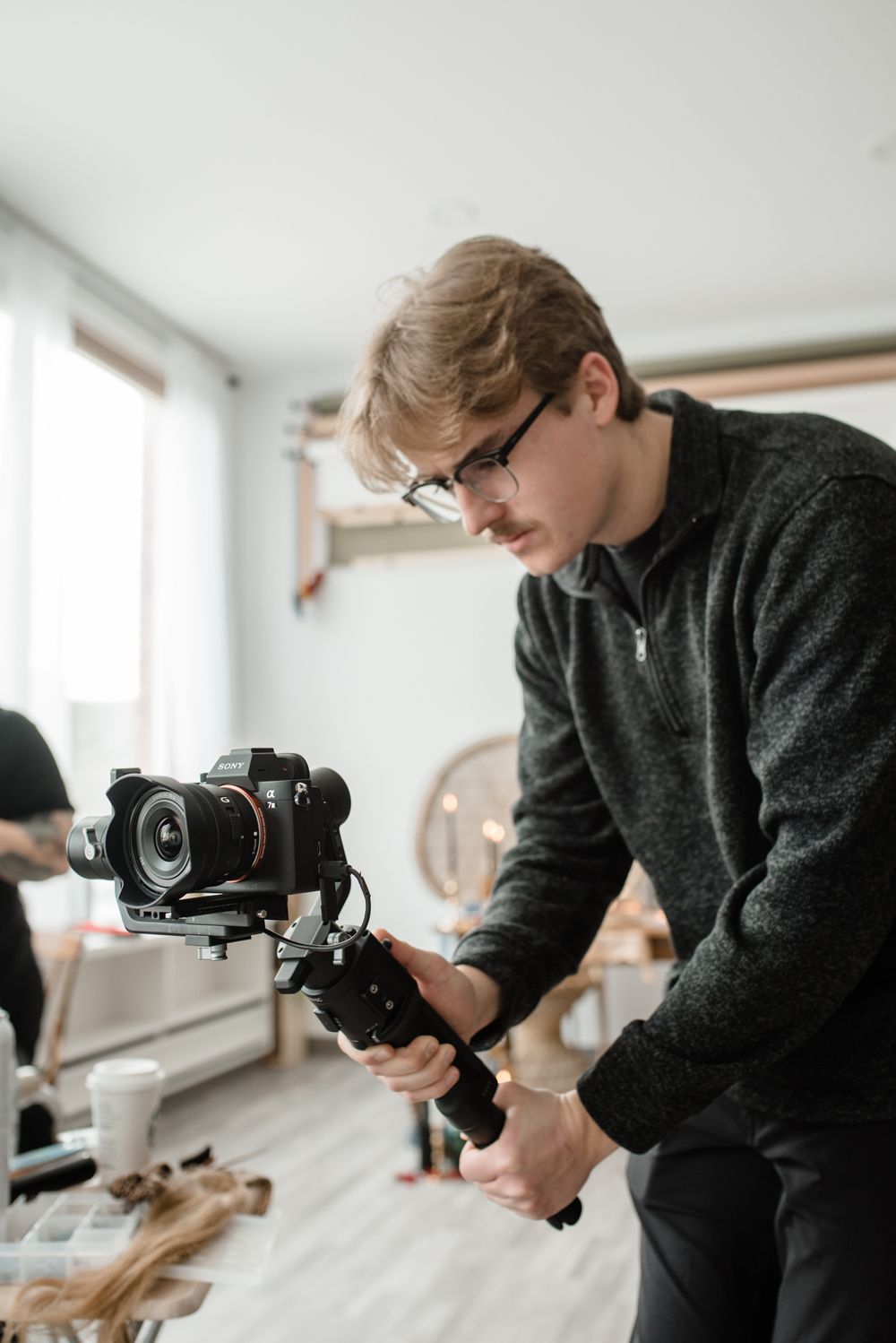 A photographer operates a professional camera gimbal setup in a bright indoor setting.