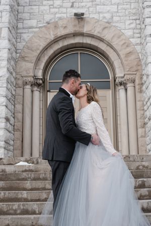 A romantic embrace on stone steps in front of an elegant arched doorway.
