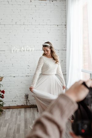 A bridal photography session against a white brick wall with neon signage.