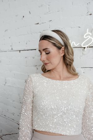 Close up of sparkly bridal crop top against white brick wall.