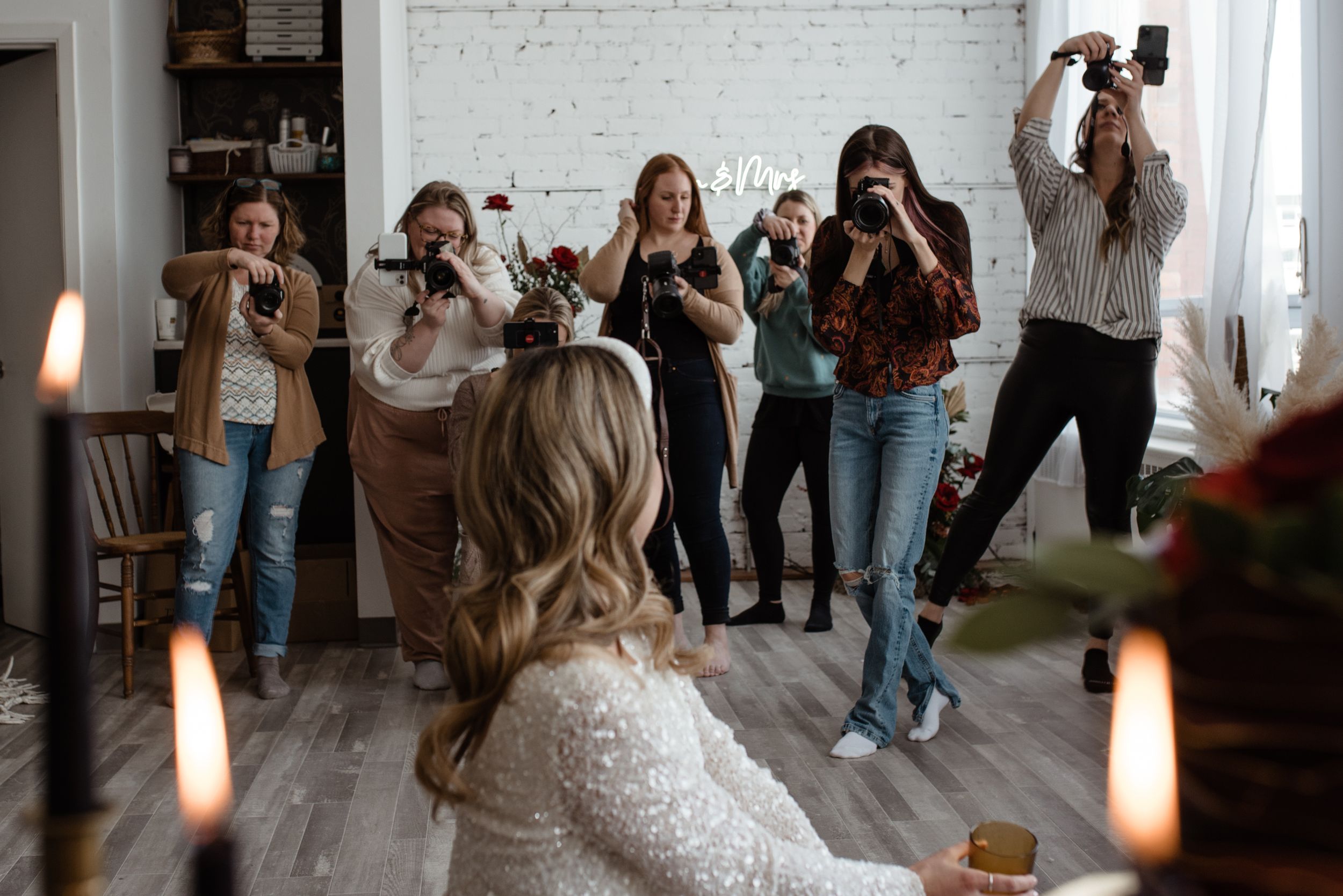 Wedding guests taking photos with their phones in a bright indoor space.