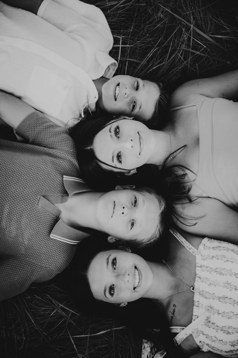 Black and white artistic photo series showing two people lying down on grass with pensive expressions in matching outfits.