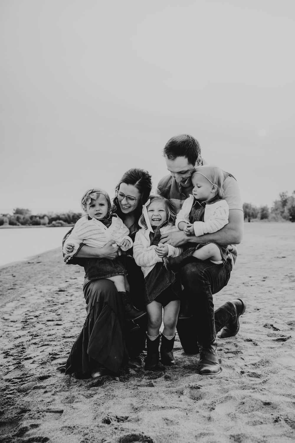 Vintage black and white photograph showing a family enjoying time together while sitting on sand at a beach.