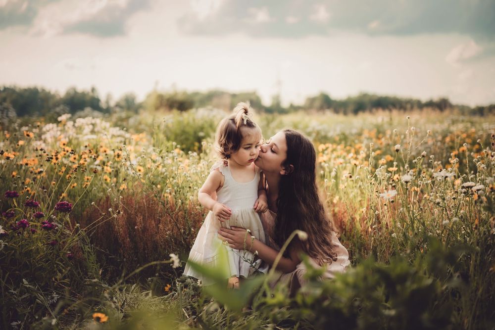 A loving moment shared between two people in a sunlit wildflower meadow on a summer afternoon.