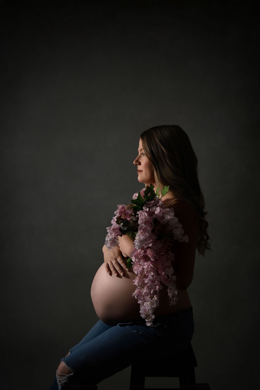 Dramatic maternity photography series showing silhouette against dark background with pink floral accents.