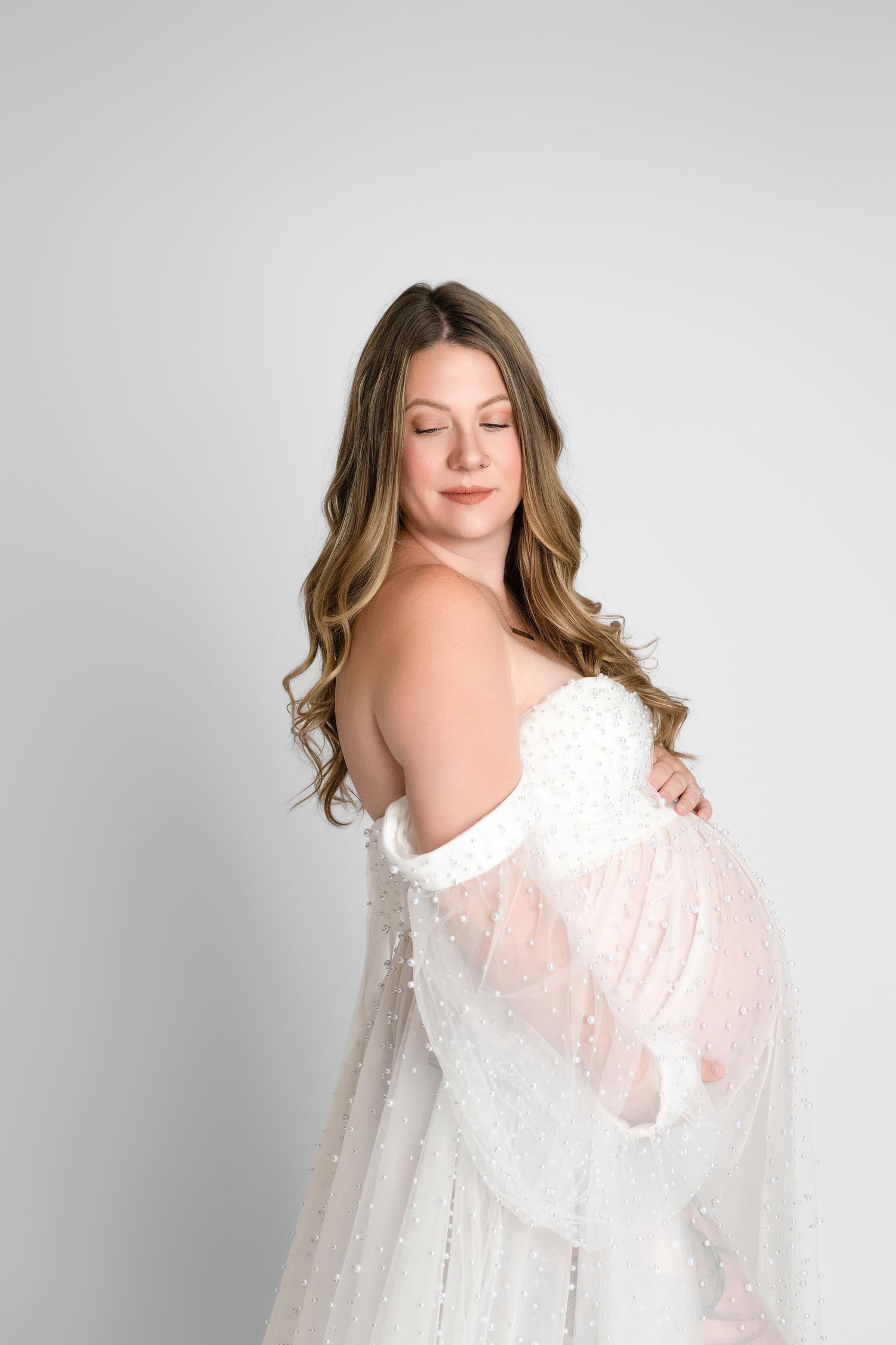 A series of four ethereal portraits featuring a white flowing lace dress against a light grey studio backdrop.