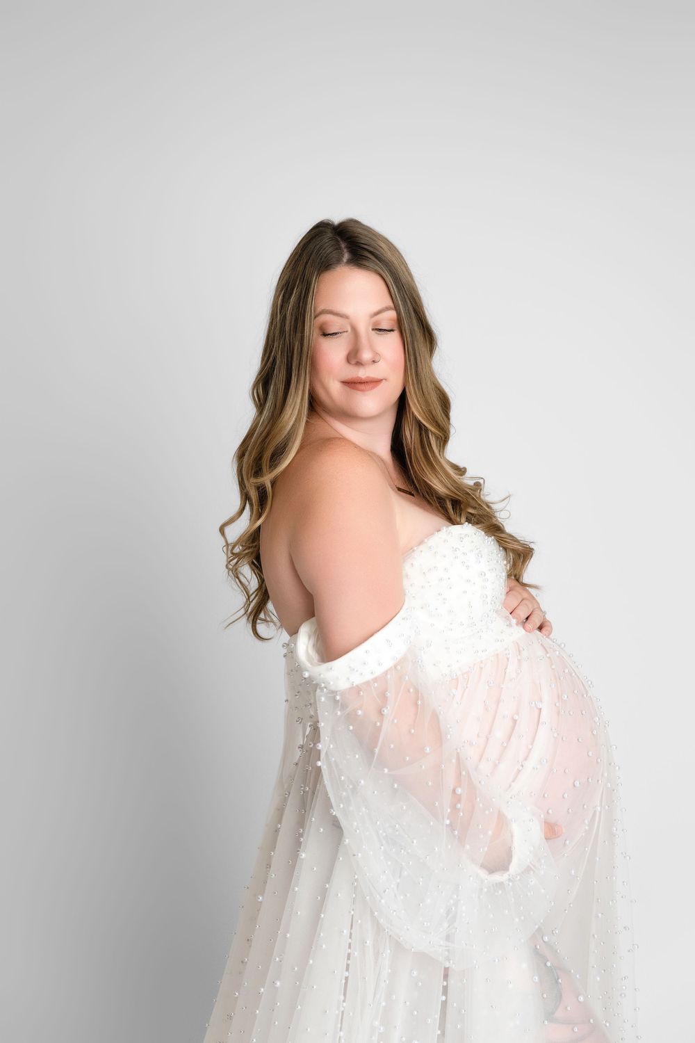 A series of four ethereal portraits featuring a white flowing lace dress against a light grey studio backdrop.