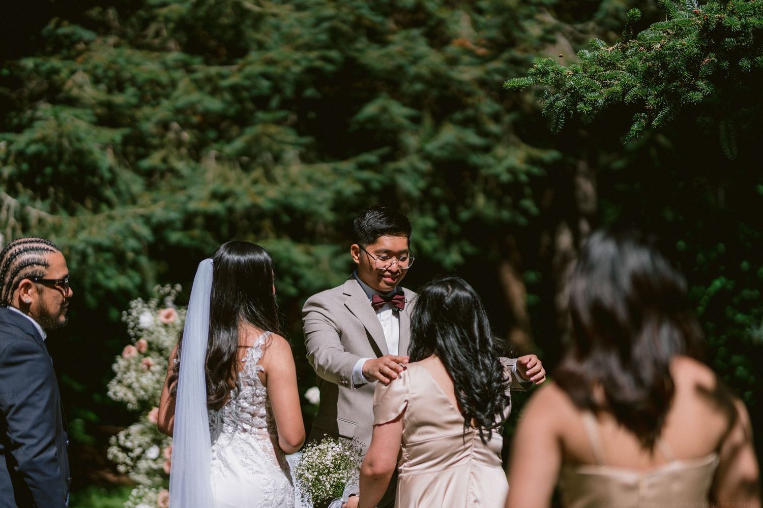Wedding guests gather in a lush outdoor forest setting during a summer ceremony.
