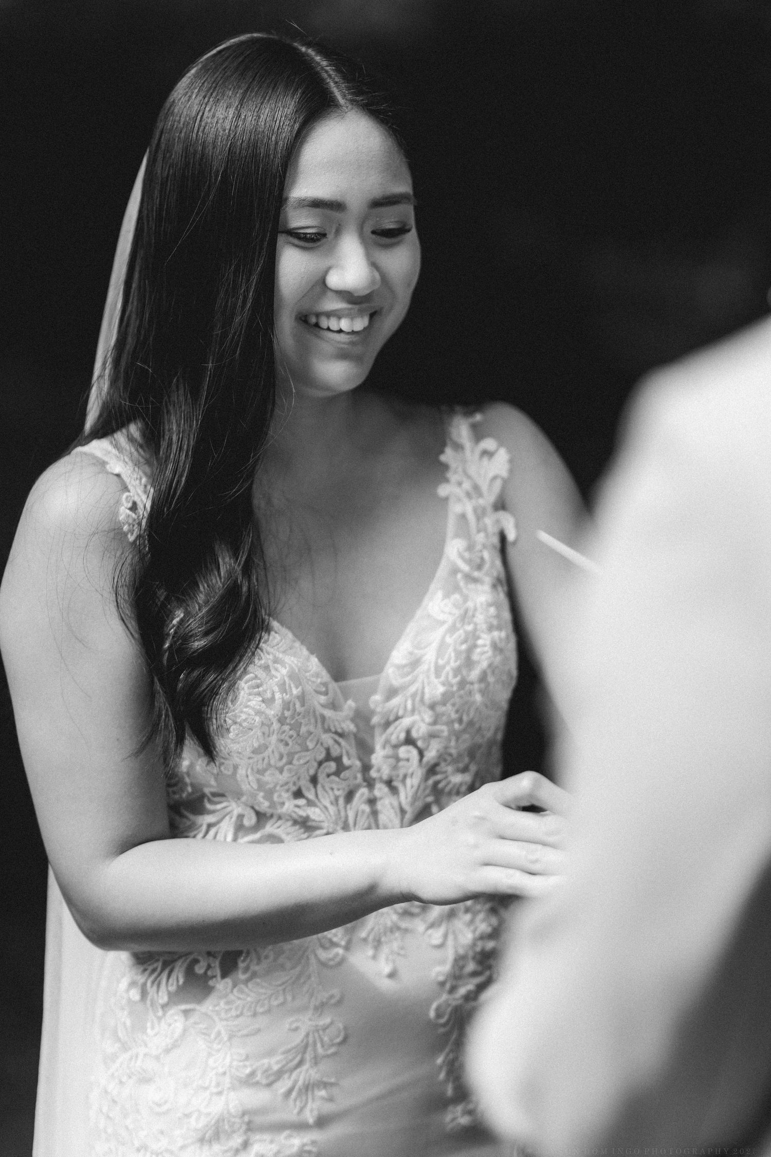 Elegant bride in lace v-neck gown smiles joyfully during her wedding celebration.