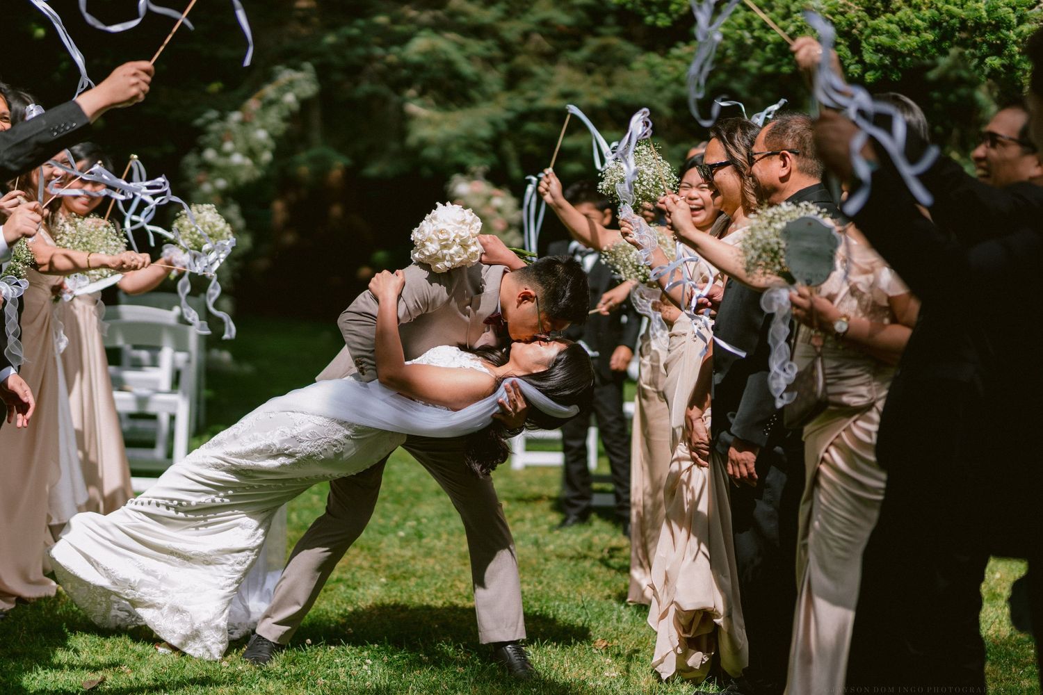A joyful scene of wedding guests dancing and celebrating outdoors in a garden setting.