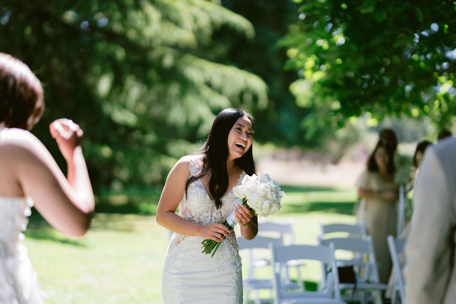 A joyful outdoor wedding celebration with white chairs set up on a lawn.