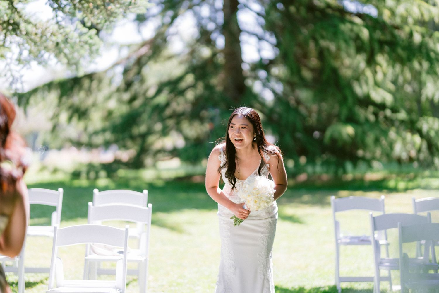 An intimate garden wedding ceremony with white folding chairs arranged on a manicured lawn.