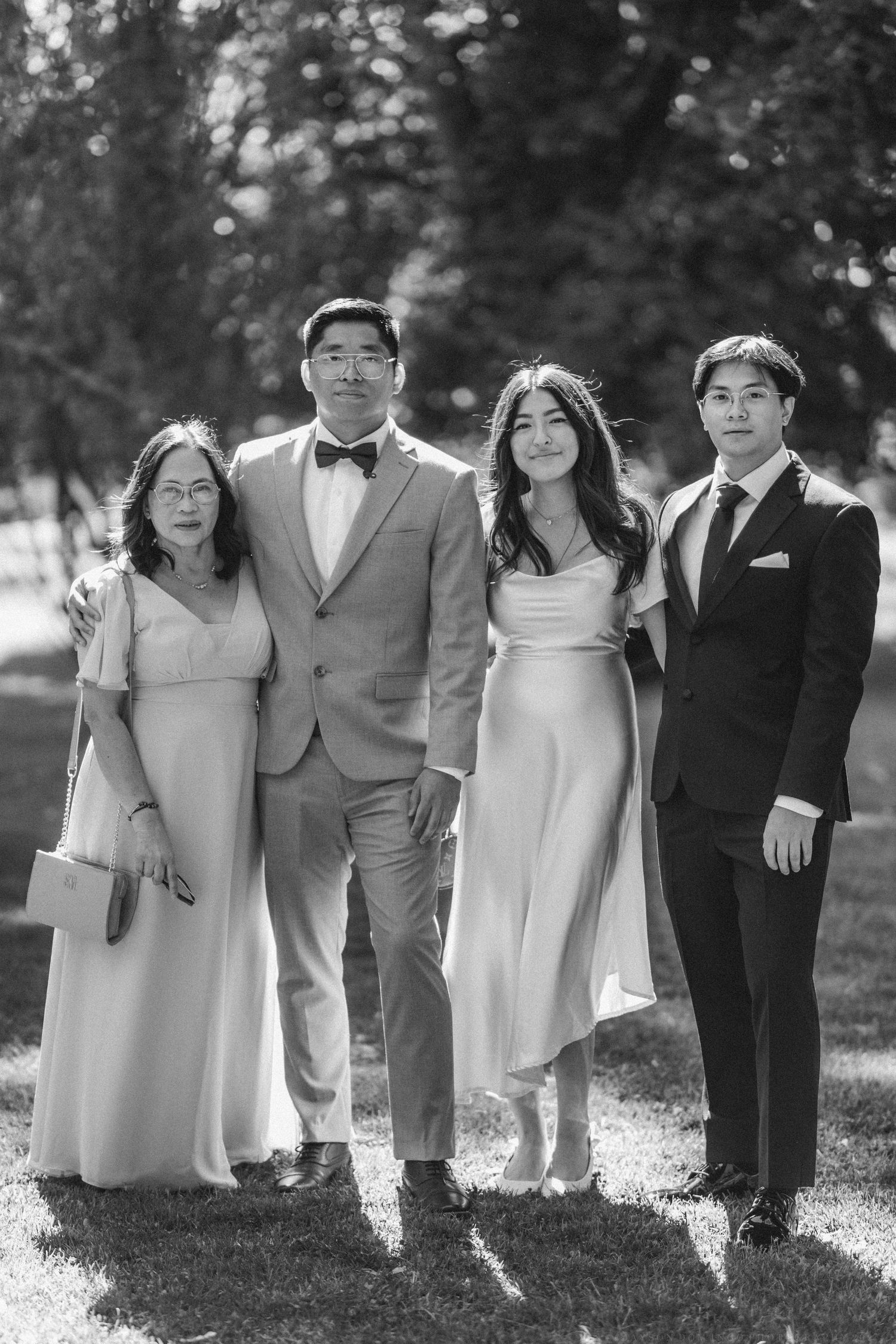 A series of black and white portraits showing children in formal attire posing together in a park setting.