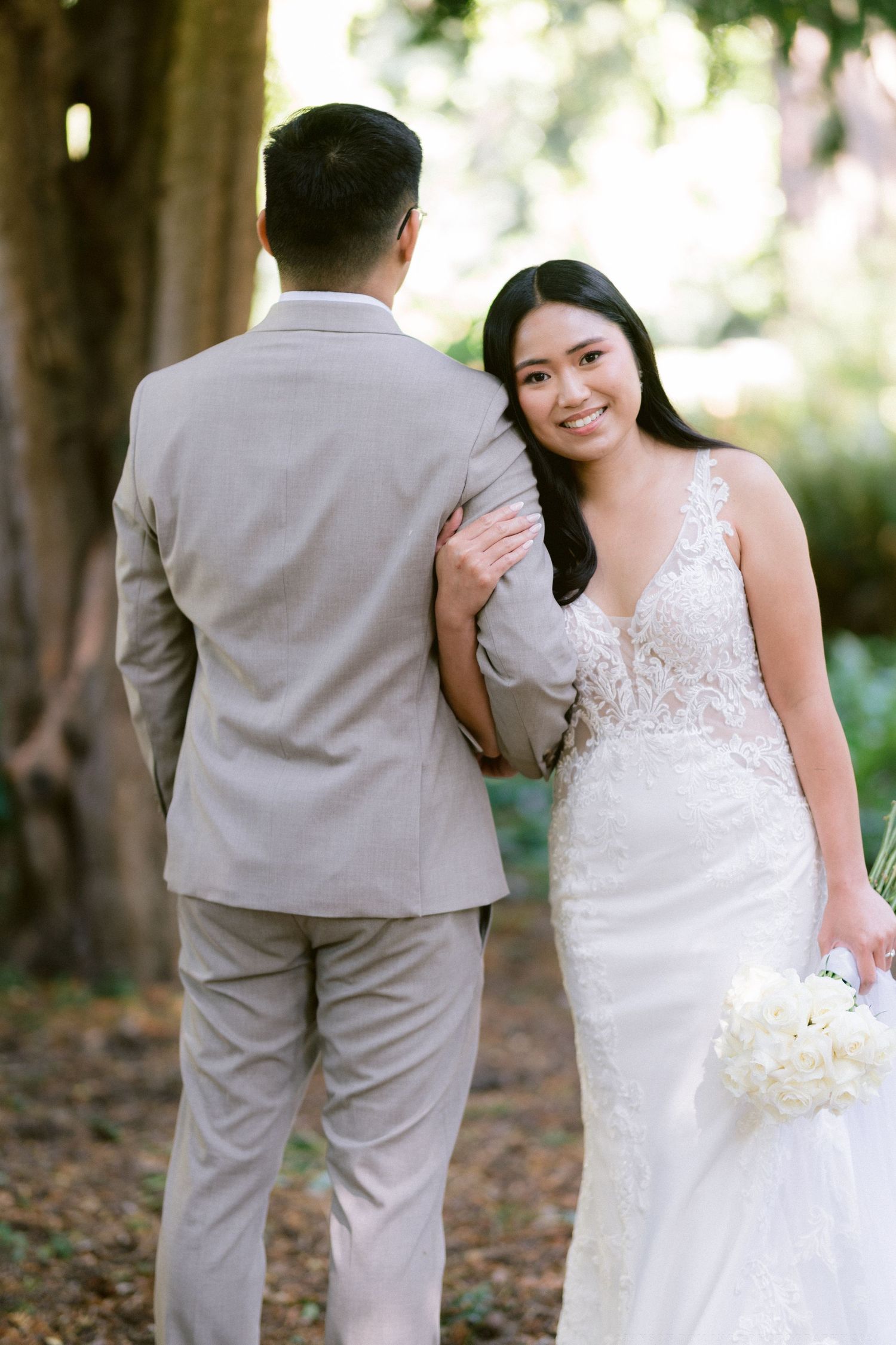 A romantic garden wedding portrait featuring a beige suit and lace wedding gown.