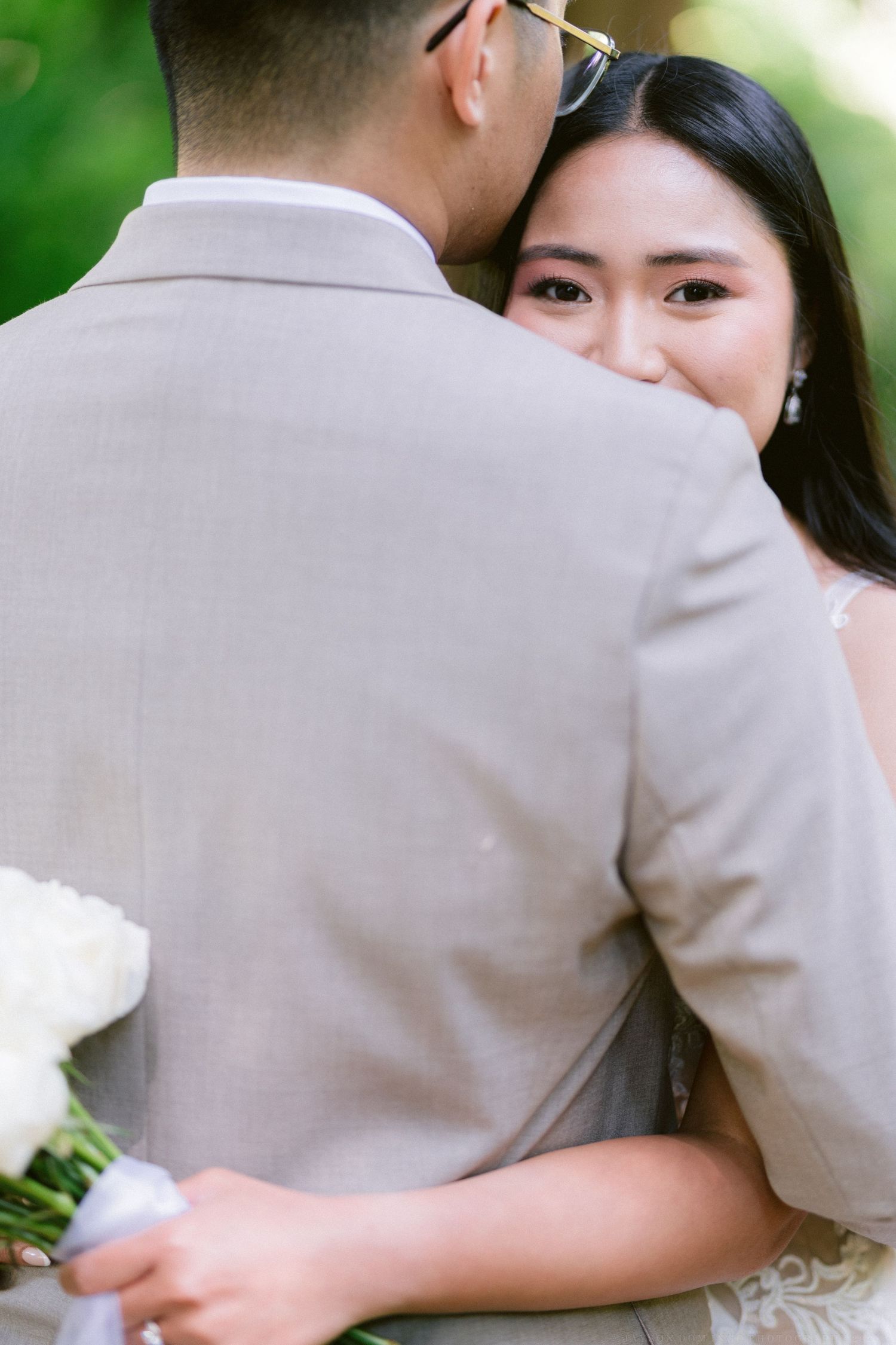 A tender moment captured between a couple during their outdoor wedding with the groom in beige suit.