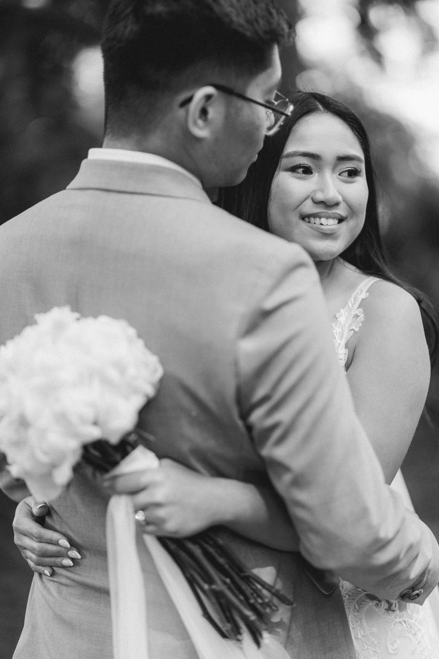 Intimate black and white portrait of newlyweds sharing a tender moment with white bouquet.