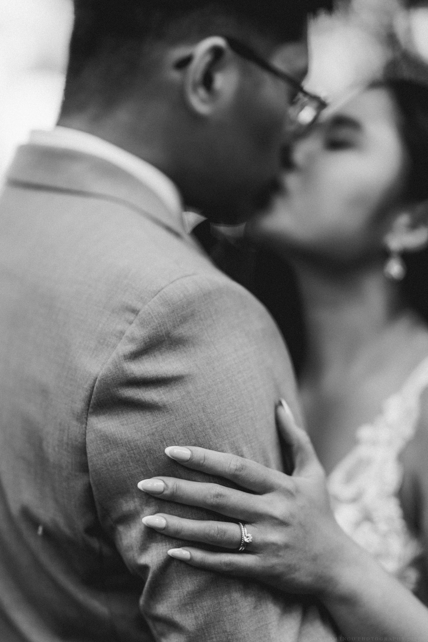 Black and white close-up of a romantic moment showing hands with wedding ring.