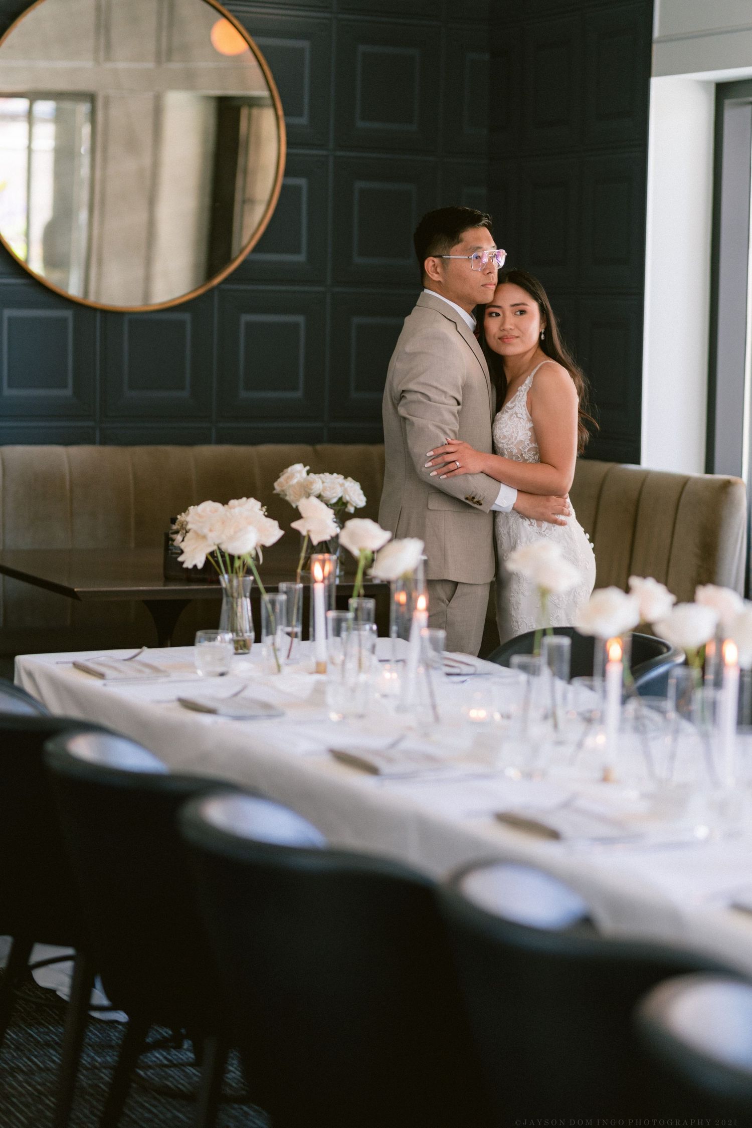 An elegant reception venue with circular mirrors and place settings visible in romantic lighting.