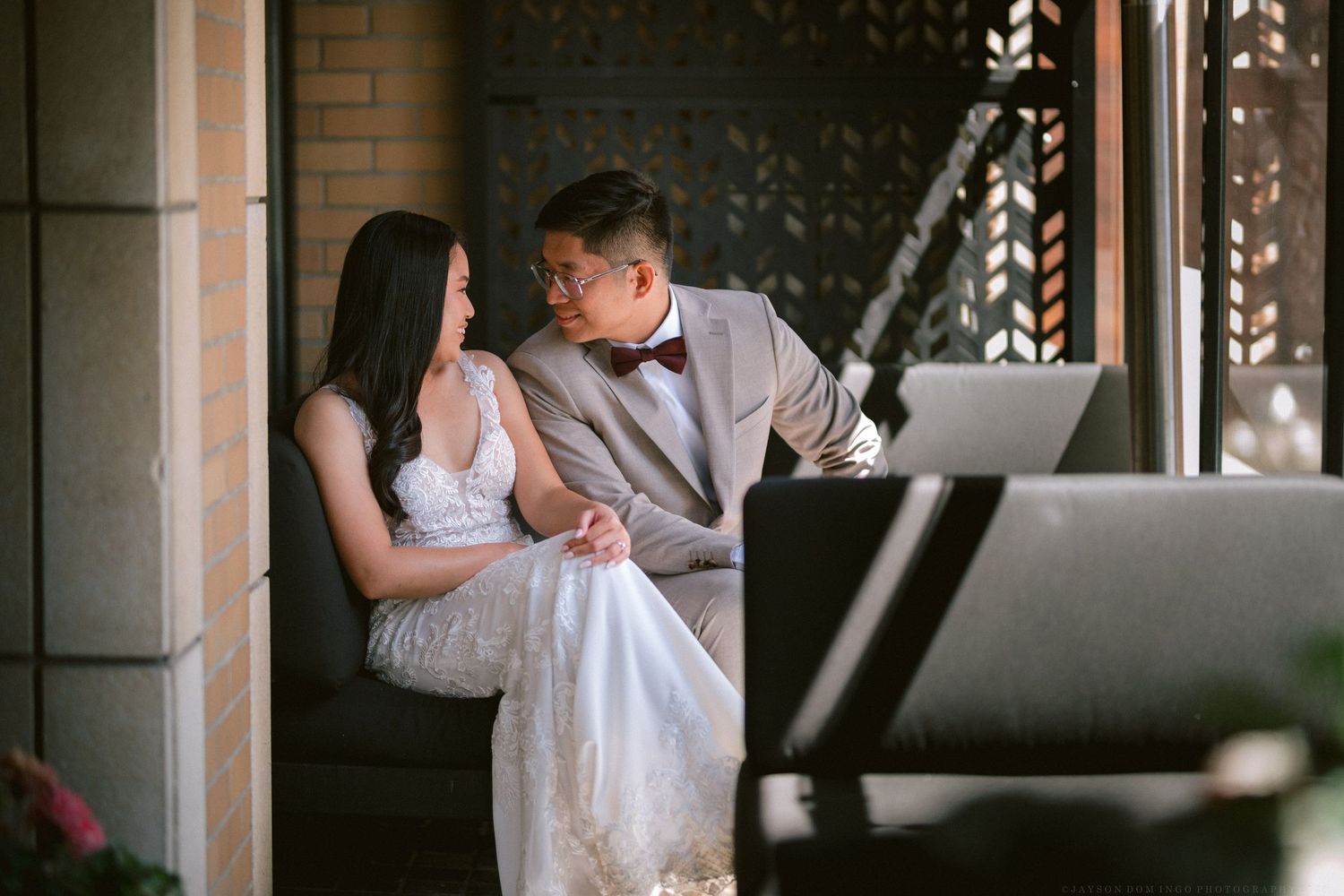 A couple in wedding attire shares an intimate moment while sitting together indoors.