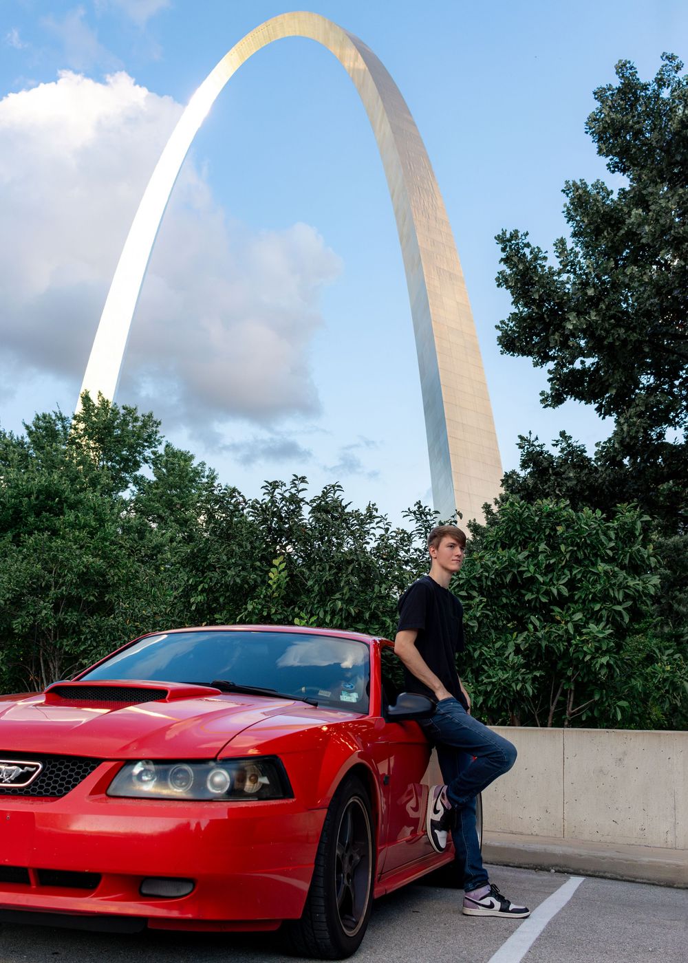 A red sports car photographed near the St. Louis Gateway Arch on a sunny day. Portrait photography. Senior Photography