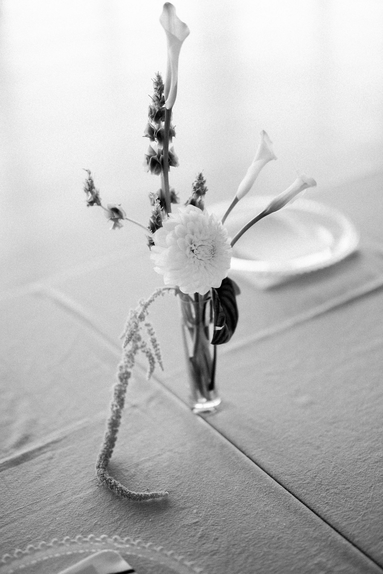 A black and white still life of delicate calla lilies and flowers in a minimalist arrangement.