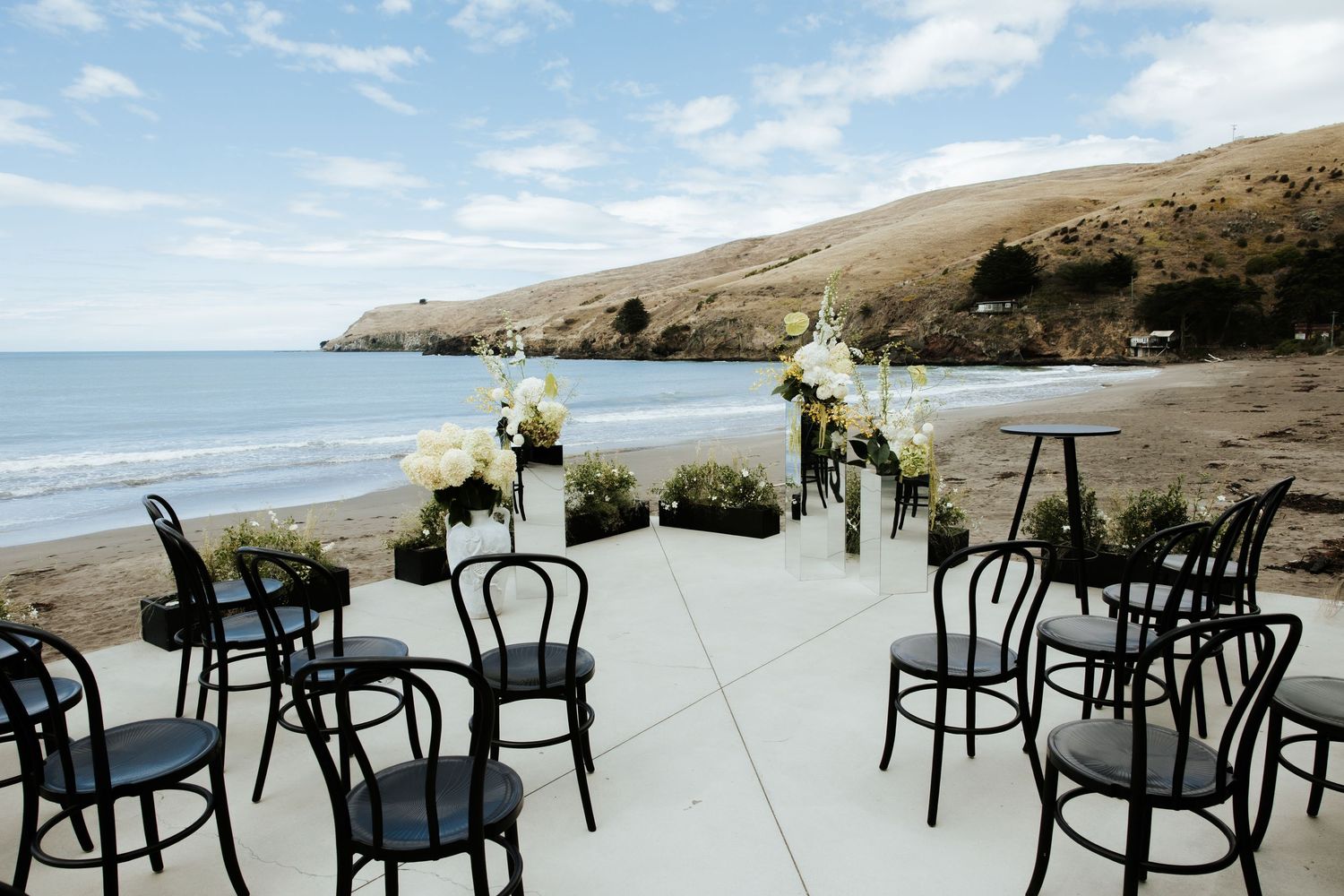 Empty chairs set up for an outdoor beach wedding ceremony with ocean views.