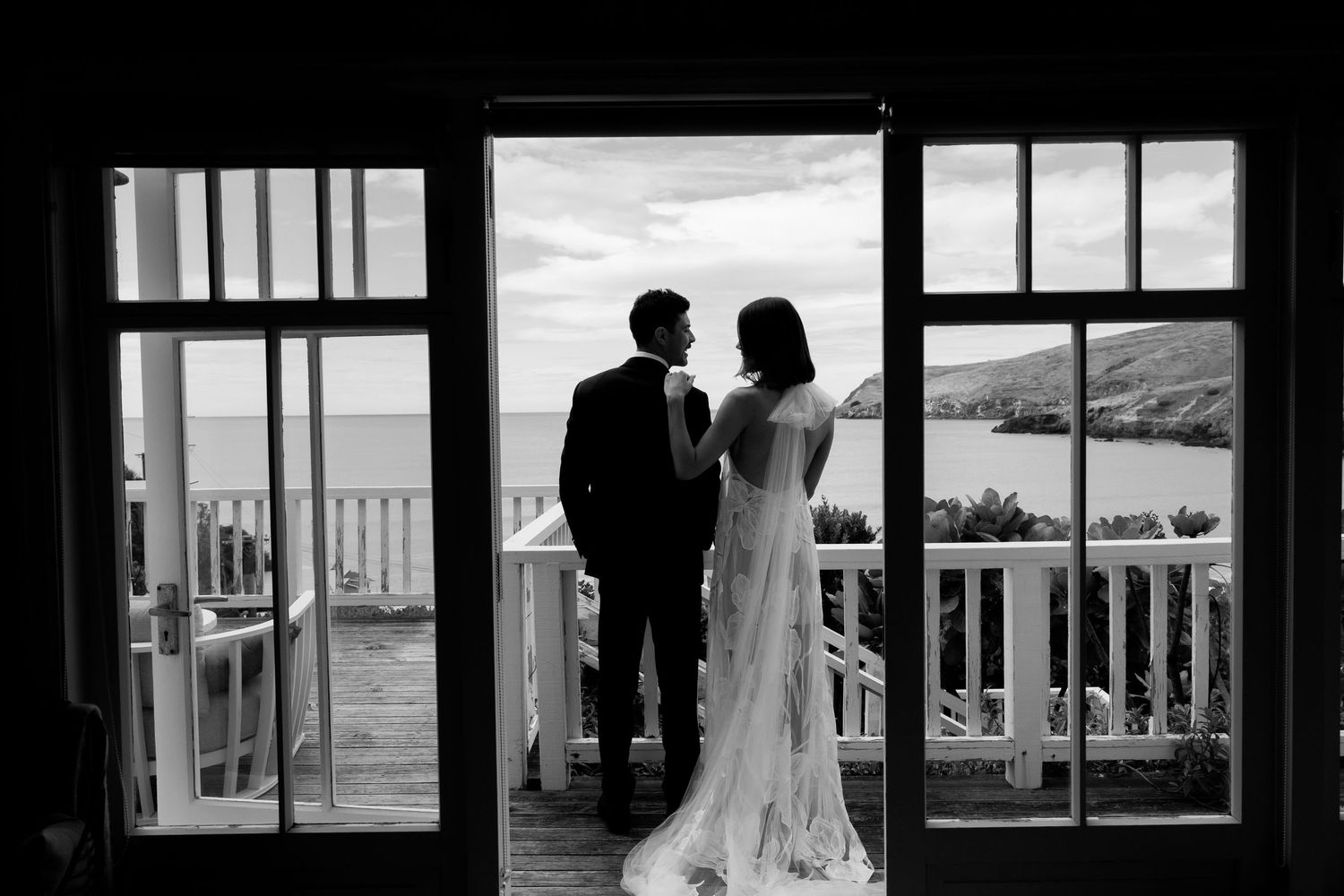 A silhouetted couple stands in a doorway overlooking coastal scenery.