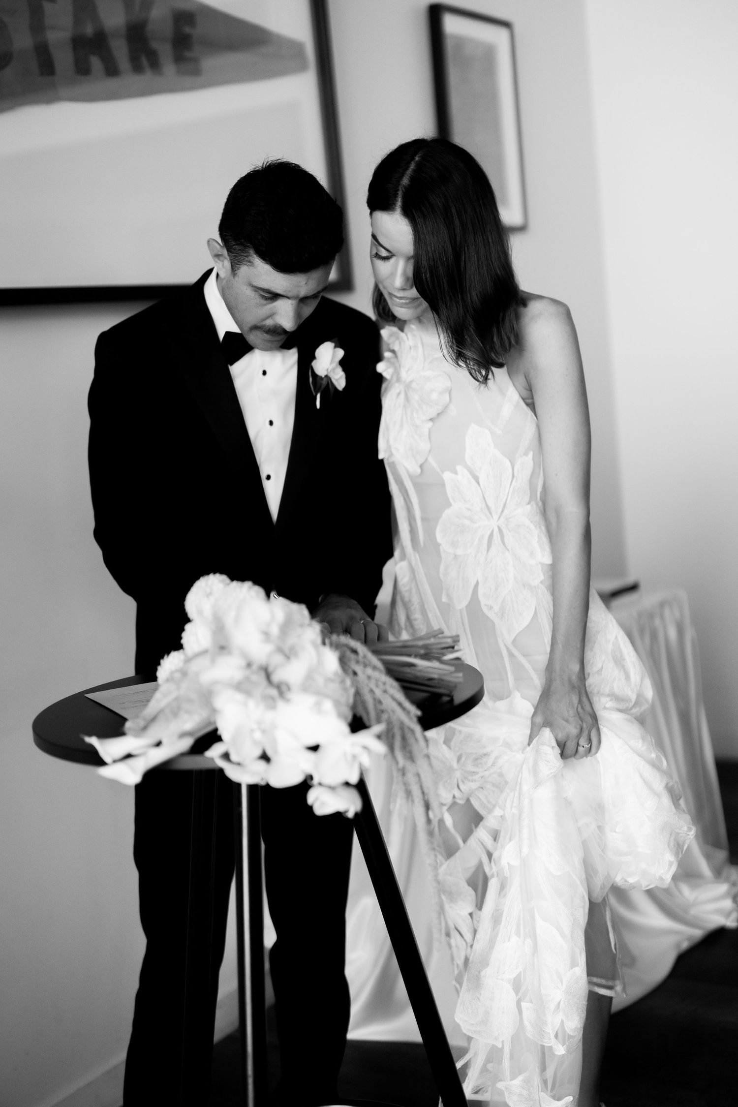 Black and white portrait of couple sharing intimate moment with wedding bouquet.
