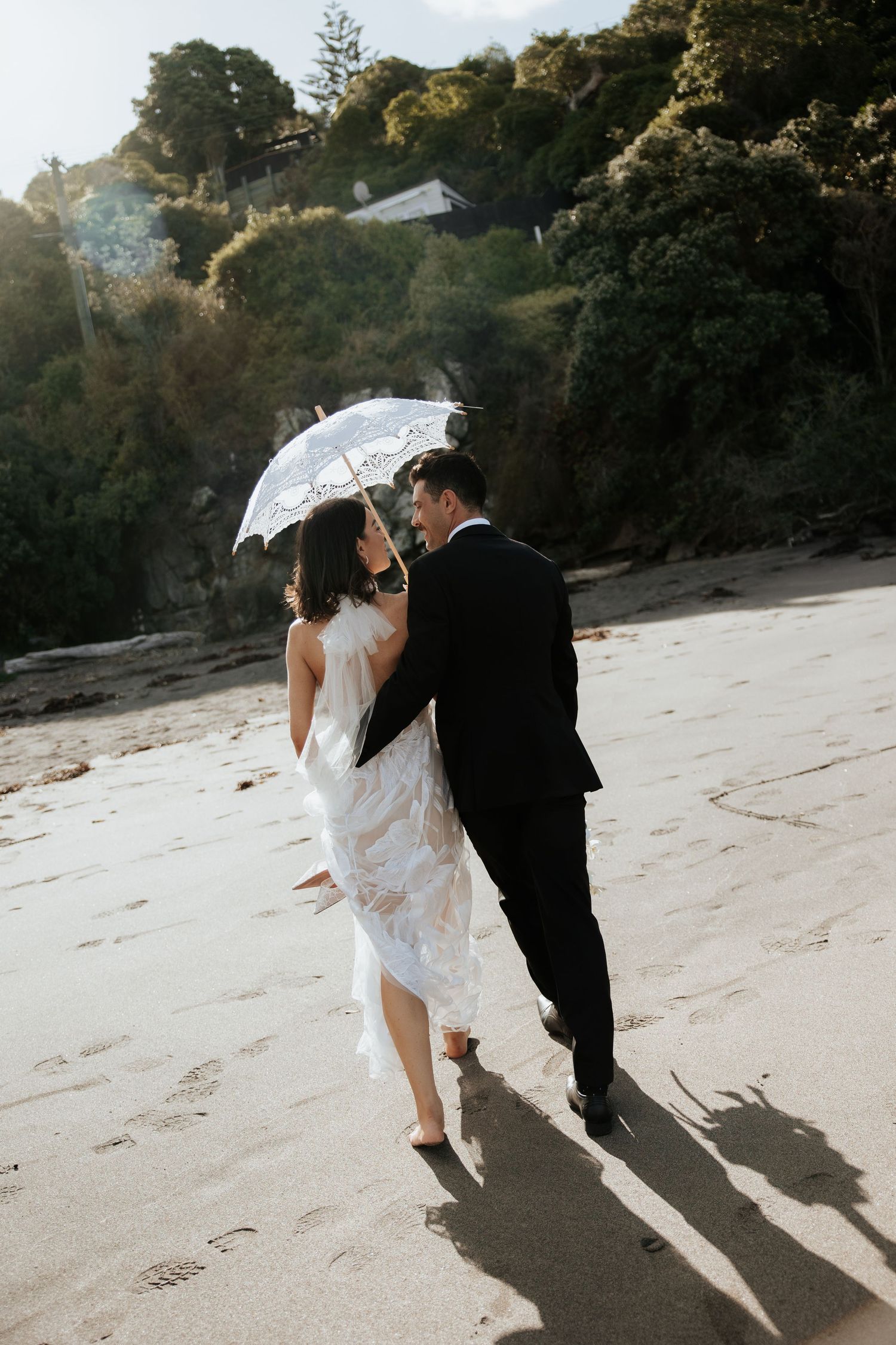 Romantic beach wedding scene with white parasol and gentle ocean breeze.
