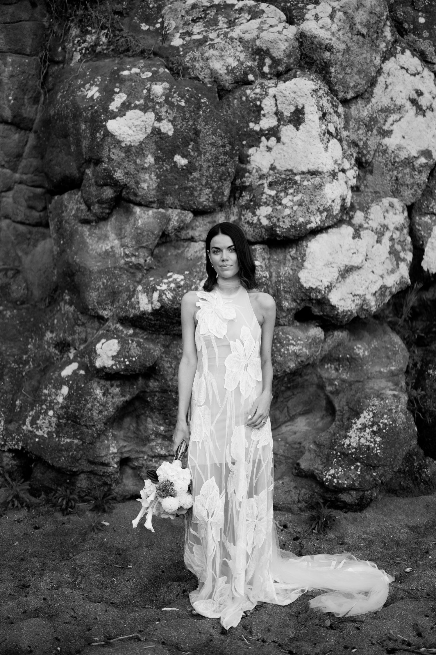 Black and white bridal portrait against textured rock wall.