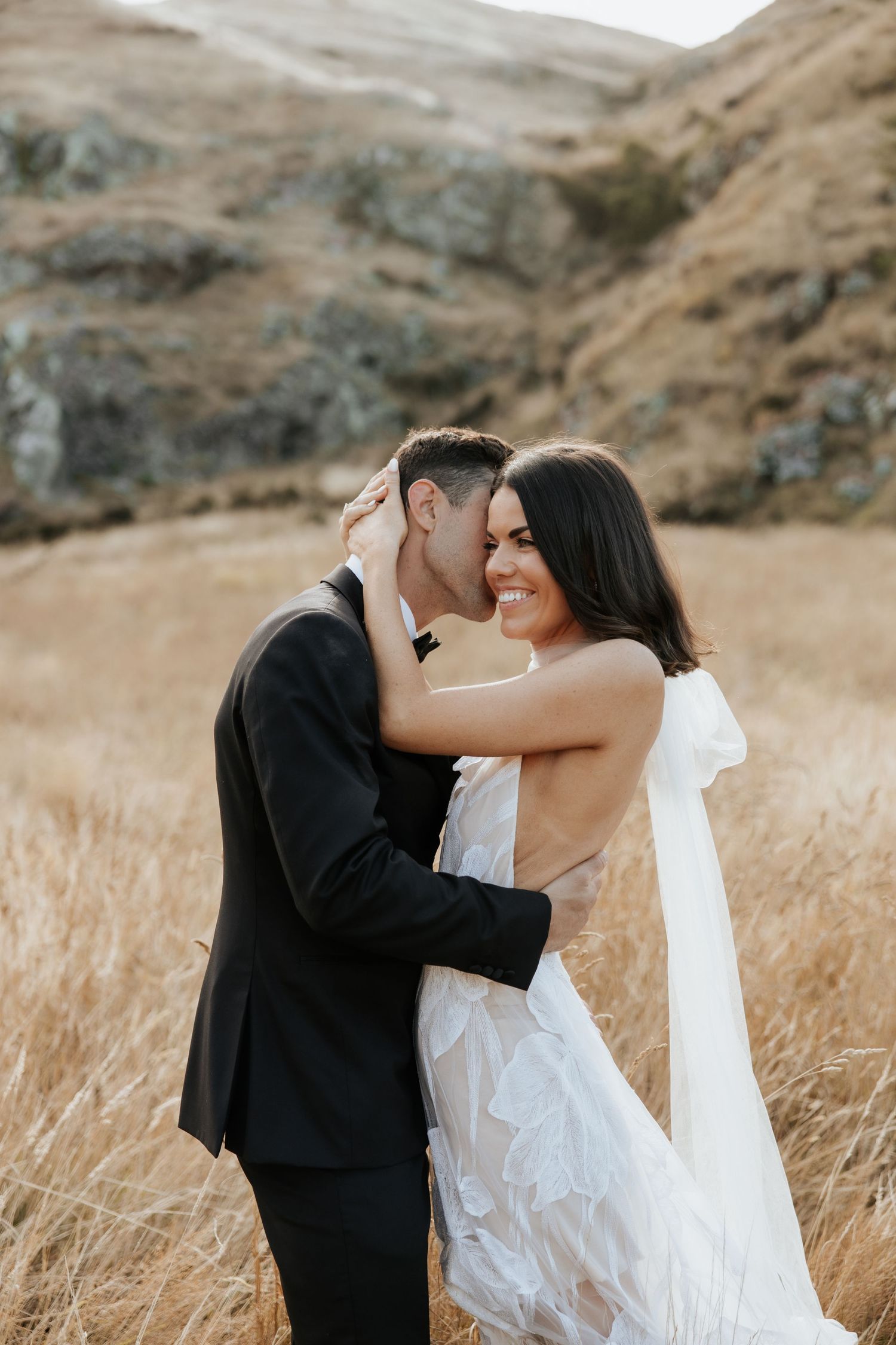 Romantic moment between newlyweds in a sun-lit field of tall grass.