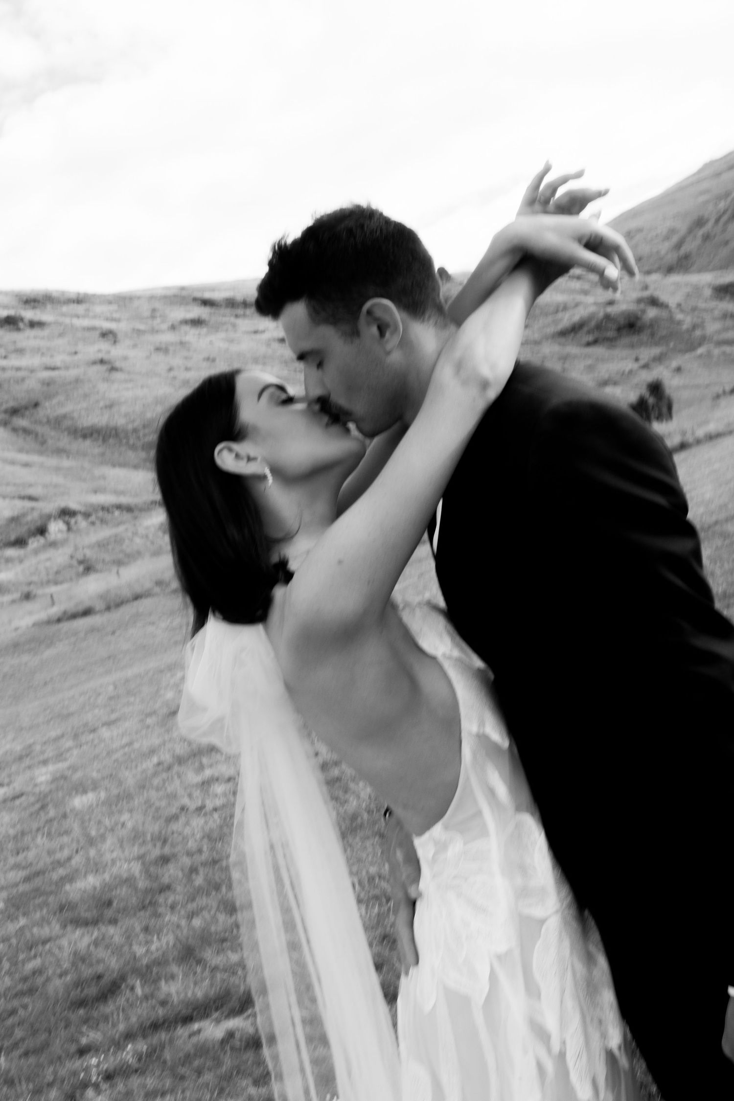 A romantic black and white photo captures a couple sharing an intimate moment in their wedding attire.